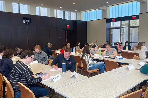 group of people sitting at tables in a class