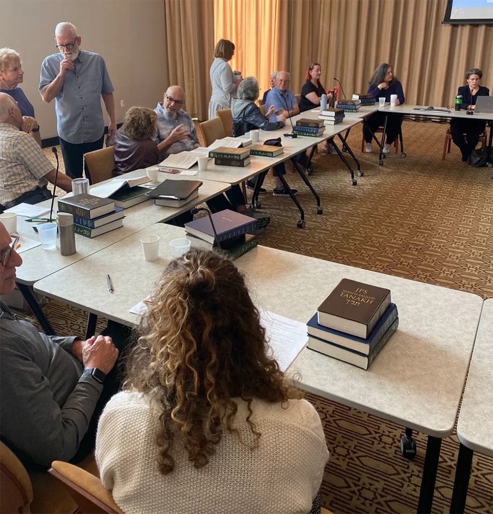 people sitting around tables studying the torah