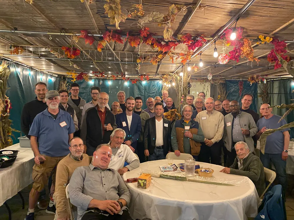 Men of RS gathered under a sukkah